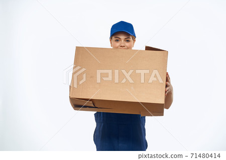 A woman in a working uniform with a box in the hands of a delivery service delivery service light background A woman in a working uniform with a box in the hands of a delivery service delivery service light background 71480414