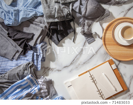 Woman is making daily to do list and schedule on notebook the organization of wardrobe in a closet. Woman is making daily to do list and schedule on notebook the organization of wardrobe in a closet. 71483033