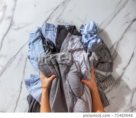 Woman hands putting stack of clean clothes for neatly tidying up and placing in steel wire wardrobe Woman hands putting stack of clean clothes for neatly tidying up and placing in steel wire wardrobe 71483048