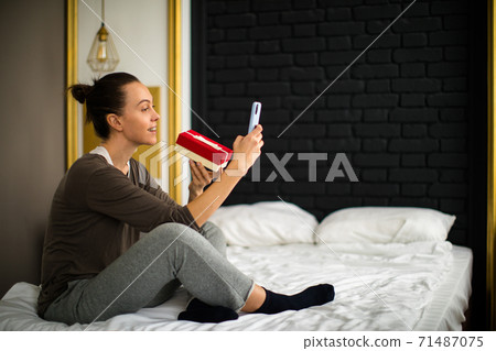 Woman showing gift by video call 71487075