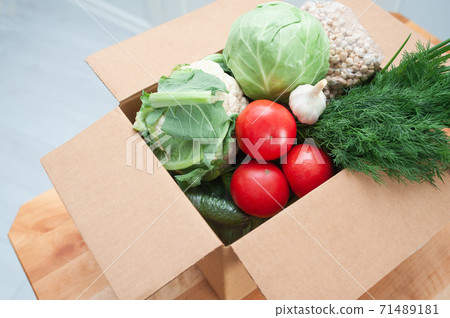 Contactless product delivery by the door. Food donation package vegetables to help the sick or poor. Donat box with foodstuffs Contactless product delivery by the door. Food donation package vegetables to help the sick or poor. Donat box with foodstuffs 71489181