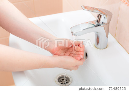 washing femle hands in a ceramic washbasin with a chrome-plated faucet under the pressure of water, the bacteria of the covid-19 virus are washed off, close up faceless. washing femle hands in a ceramic washbasin with a chrome-plated faucet under the pressure of water, the bacteria of the covid-19 virus are washed off, close up faceless. 71489523