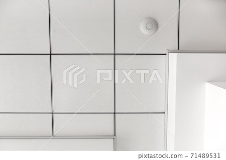 multi-level ceiling with three-dimensional protrusions and a suspended tiled ceiling white color, close up geometric empty details, view from bottom. 71489531