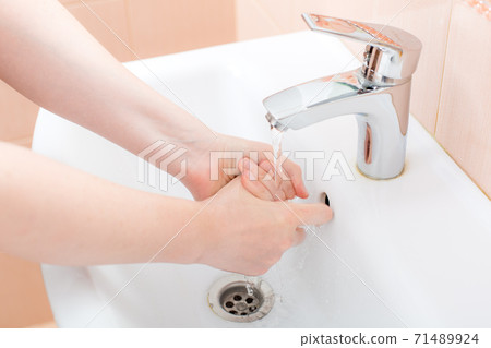 washing femle hands in white ceramic washbasin with a chrome faucet under pressure of water, bacteria of covid-19 virus are washed off, close up faceless. washing femle hands in white ceramic washbasin with a chrome faucet under pressure of water, bacteria of covid-19 virus are washed off, close up faceless. 71489924