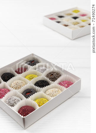Two boxes of vegan sweets energy balls on white wooden table. Two boxes of vegan sweets energy balls on white wooden table. 71490274