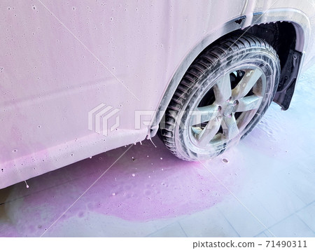 car wash for cleaning dirty cars and caring for the body of an SUV, close-up of a door and a fender with a wheel covered with active foam and wax. car wash for cleaning dirty cars and caring for the body of an SUV, close-up of a door and a fender with a wheel covered with active foam and wax. 71490311