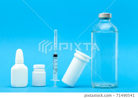 medicines for the treatment of diseases in plastic bottles and a vaccine in a glass bottle with an injection syringe, concept medical theme on a blue background. medicines for the treatment of diseases in plastic bottles and a vaccine in a glass bottle with an injection syringe, concept medical theme on a blue background. 71490541