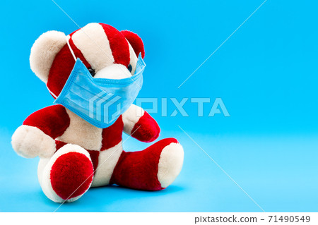 Teddy bear in a medical mask on a blue background with copy space, concept medical background. 71490549