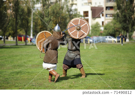 Reenactors dressed in armor of Old Russian footmen reconstructing swords fight Reenactors dressed in armor of Old Russian footmen reconstructing swords fight 71490812