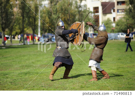 Reenactors dressed in armor of Old Russian footmen reconstructing swords fight Reenactors dressed in armor of Old Russian footmen reconstructing swords fight 71490813
