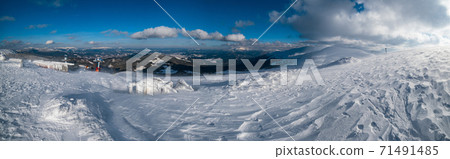 Snow covered mountain slope in last evening sunlight. Magnificent windy dusk on tops above picturesque alpine ski resort, Dragobrat, Ukraine, Carpathian Mountains. 71491485
