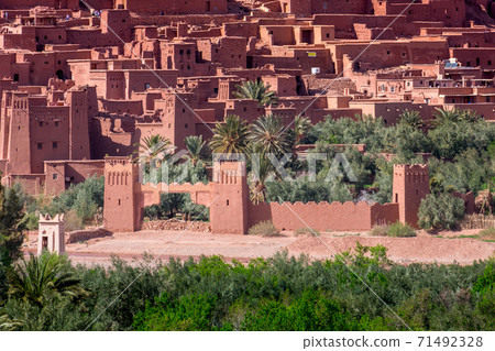 Daytime close up shot of Ksar de Ait Ben Haddou, with its abobe houses, surrounded by palm trees. Morocco. Daytime close up shot of Ksar de Ait Ben Haddou, with its abobe houses, surrounded by palm trees. Morocco. 71492328