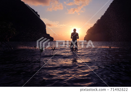 Men playing with sea water in the morning by the beach at sunrise. 71492822