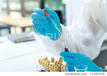 Researcher or scientists loads liquid sample into test tube in laboratory. Researchers are developing vaccines and medicine to treat the COVID-19 virus. 71493359