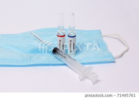 Two medicine ampule with anti covid-19 vaccine and syringe on protection mask on white background 71495761