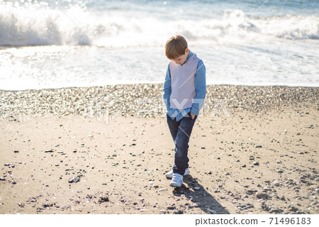 The baby boy walks along the sandy beach along the coast. The baby boy walks along the sandy beach along the coast. 71496183
