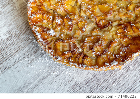 Homemade baking. Freshly baked apple pie on a light wooden background sprinkled with icing sugar. Homemade baking. Freshly baked apple pie on a light wooden background sprinkled with icing sugar. 71496222