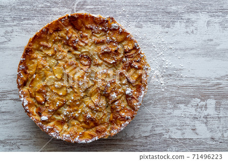 Homemade baking. Freshly baked apple pie on a light wooden background sprinkled with icing sugar. Homemade baking. Freshly baked apple pie on a light wooden background sprinkled with icing sugar. 71496223