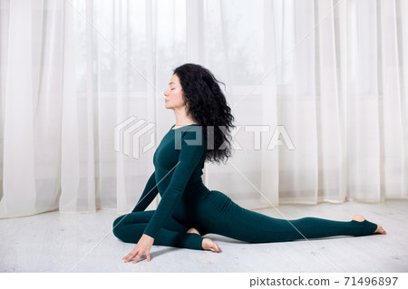 girl in sportswear doing yoga exercises sitting on the floor in the room during quarantine stay home safe world. girl in sportswear doing yoga exercises sitting on the floor in the room during quarantine stay home safe world. 71496897