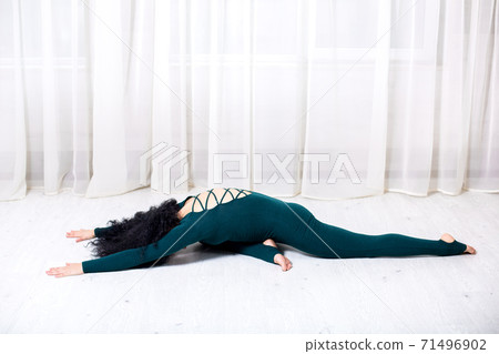 girl in sportswear doing yoga exercises lying on the floor in the room during quarantine stay home work safe world. girl in sportswear doing yoga exercises lying on the floor in the room during quarantine stay home work safe world. 71496902