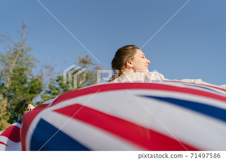 Britain's flag beautifully develops in the hands behind a woman 71497586