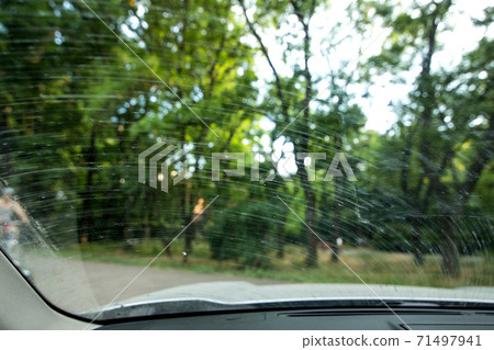 windshield in dirty stains from the swamp and dust smeared by the wipers, close up from inside the dirty car. 71497941