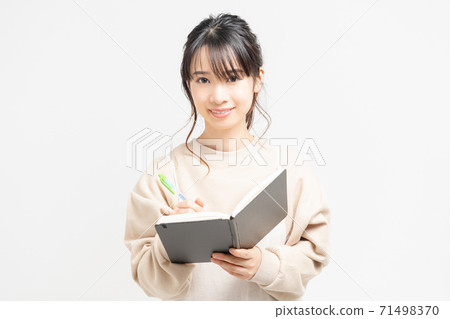 Young woman writing notes in a notebook Young woman writing notes in a notebook 71498370