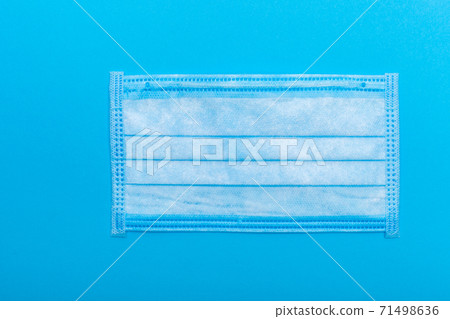 medical mask to protect the respiratory tract from virus respiratory diseases, a hygiene object isolated on a blue background with a space place. medical mask to protect the respiratory tract from virus respiratory diseases, a hygiene object isolated on a blue background with a space place. 71498636