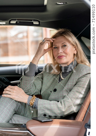 Smiling elegant businesswoman looking at you from backseat of taxi cab Smiling elegant businesswoman looking at you from backseat of taxi cab 71499110