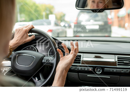 Hands of mature businesswoman expressing annoyance with the car in front 71499119