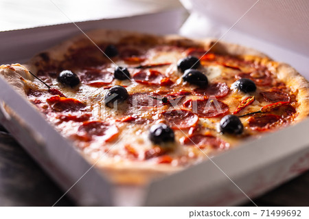 Pizza in a cardboard box on table ready to Pizza in a cardboard box on table ready to 71499692