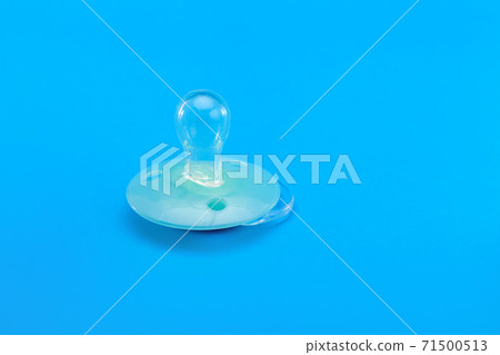 light blue baby pacifier lies on a blue background, object baby accessories with a copy space. light blue baby pacifier lies on a blue background, object baby accessories with a copy space. 71500513