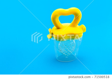 Fruit feeder for feeding weaned babies on a blue background with a copy space, nobody. Fruit feeder for feeding weaned babies on a blue background with a copy space, nobody. 71500518