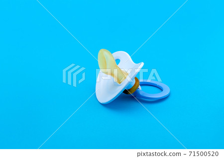 a blue pacifier made of soft silicone isolated on blue background side view with copy space. a blue pacifier made of soft silicone isolated on blue background side view with copy space. 71500520