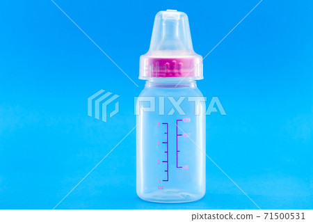 feeding bottle with pacifier and measuring scale, transparent plastic bottle with a cap isolated on a blue background with copy space. 71500531