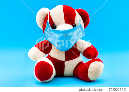 Teddy bear in a sick mask on a blue background with copy space, conceptual medical background. 71500533