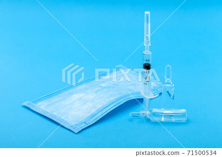 medical mask and syringe with ampoules for injection of a viral disease, conceptual background on the topic of pharmacology and vaccines for diseases with copy space. medical mask and syringe with ampoules for injection of a viral disease, conceptual background on the topic of pharmacology and vaccines for diseases with copy space. 71500534
