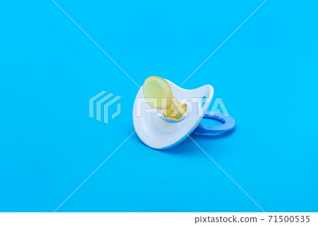 a pacifier with a bite for babies made of soft silicone, baby care facility isolated on blue background with copy space. a pacifier with a bite for babies made of soft silicone, baby care facility isolated on blue background with copy space. 71500535