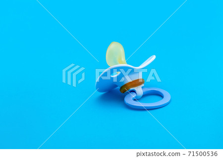 a pacifier with a bite for babies made of soft silicone, soother isolated on blue background with copy space. 71500536