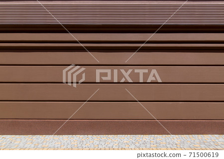 architecture brown facade of building with rustication and stripes with protective layer from moisture and water along the bottom of facade along the pedestrian walkway made of stone tiles, nobody. 71500619