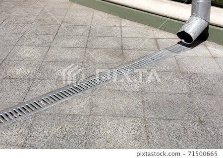 engineering structure downspout on facade building with drainage grate of a gray stone granite sidewalk from square tiles on floor, closeup details city infrastructure, nobody. engineering structure downspout on facade building with drainage grate of a gray stone granite sidewalk from square tiles on floor, closeup details city infrastructure, nobody. 71500665