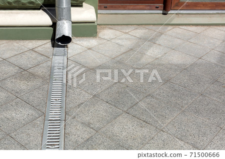 engineering structure downspout on facade building with drainage grate of gray stone granite sidewalk from square tiles on floor with copy space, closeup details city infrastructure, nobody. engineering structure downspout on facade building with drainage grate of gray stone granite sidewalk from square tiles on floor with copy space, closeup details city infrastructure, nobody. 71500666