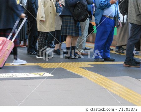 At the feet of people waiting for the train 71503872