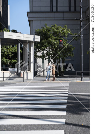 A Japanese woman asked for directions by a foreign woman while waiting for a traffic light at an intersection 71506126