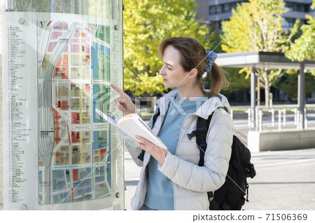 Foreign women looking for a place on a guide map in the city 71506369