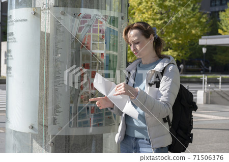 Foreign women looking for a place on a guide map in the city Foreign women looking for a place on a guide map in the city 71506376