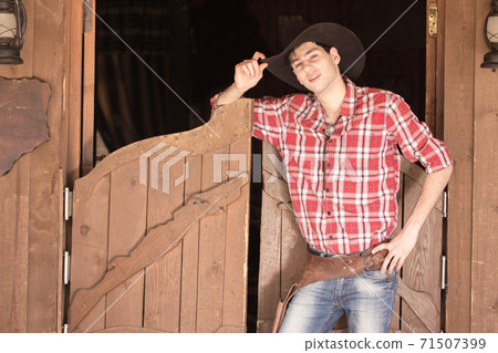 Cowboy in hat standing near saloon entrance Cowboy in hat standing near saloon entrance 71507399
