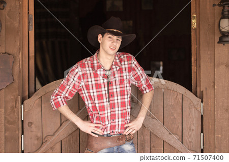 Cowboy in hat standing near saloon entrance Cowboy in hat standing near saloon entrance 71507400