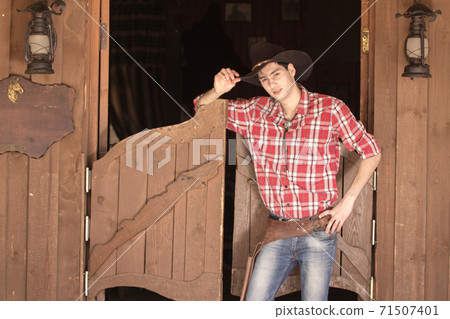 Cowboy in hat standing near saloon entrance 71507401