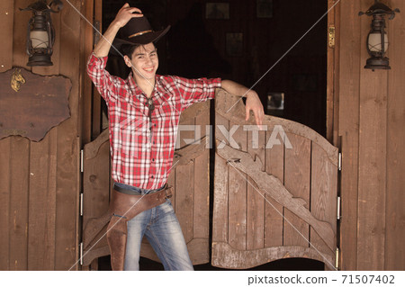 Cowboy in hat standing near saloon entrance Cowboy in hat standing near saloon entrance 71507402